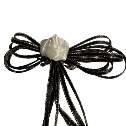 Hair bow made of black ribbons with a white center on a white background