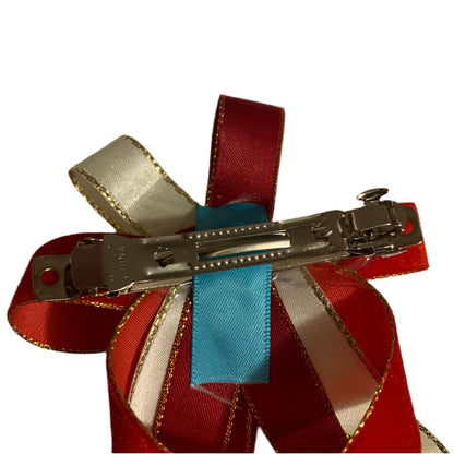 Hair clip with red, gold, and blue ribbons on a white background