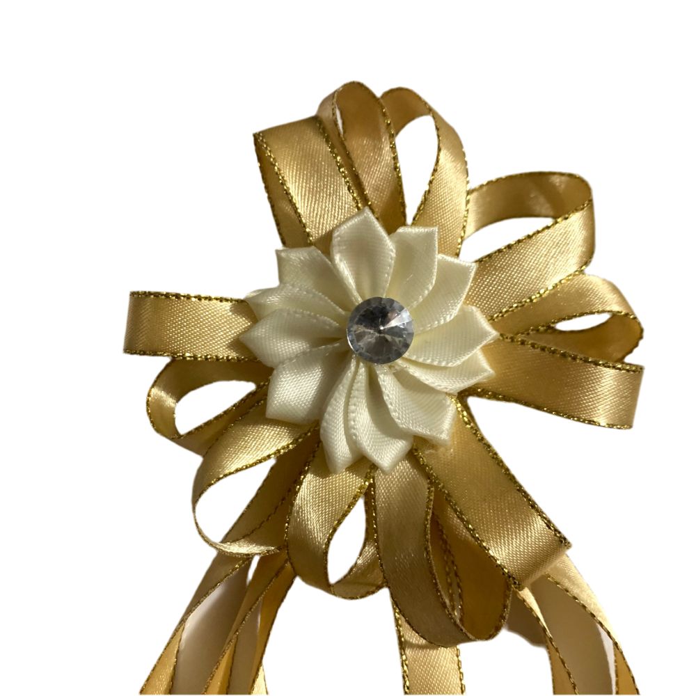 Decorative bow with gold ribbons and a white flower center on a white background