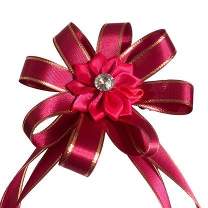 Pink bow with gold accents and a central flower design on a white background