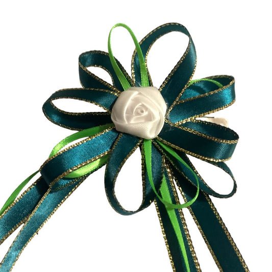 Decorative hair bow with green ribbons and a white rose on a white background