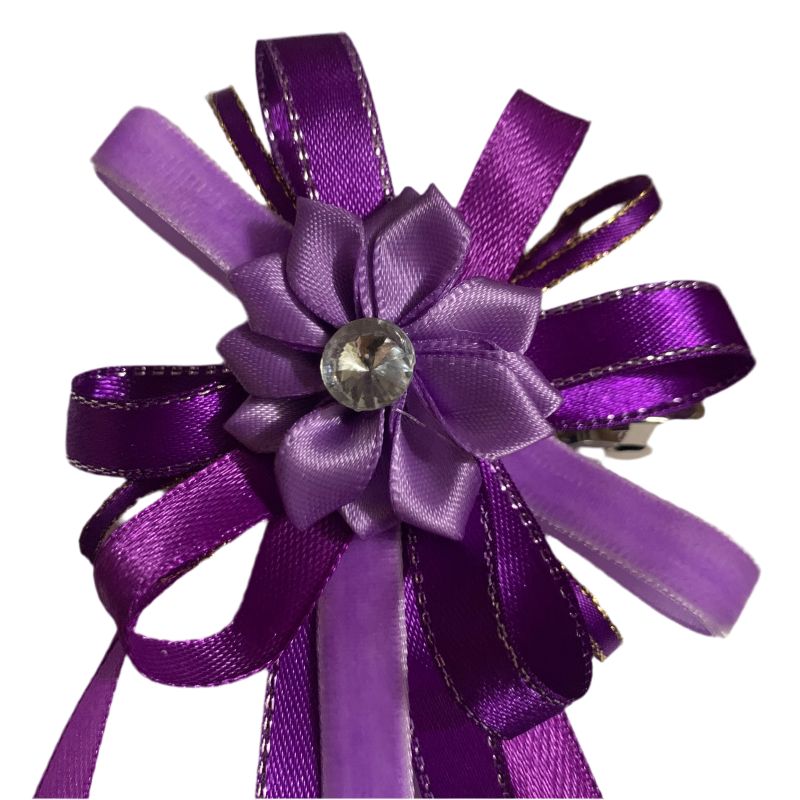 Purple ribbon flower with a central gemstone hair bow on a white background