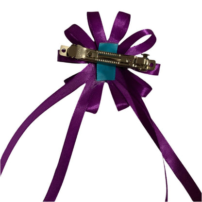 Purple ribbon bow with a silver clip on a white background