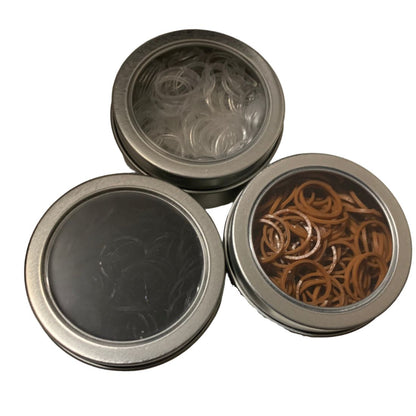 Three metal tins with lids,  showing rubber plaiting bands, on a white background